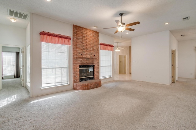 unfurnished living room with ceiling fan, light carpet, a textured ceiling, and a fireplace