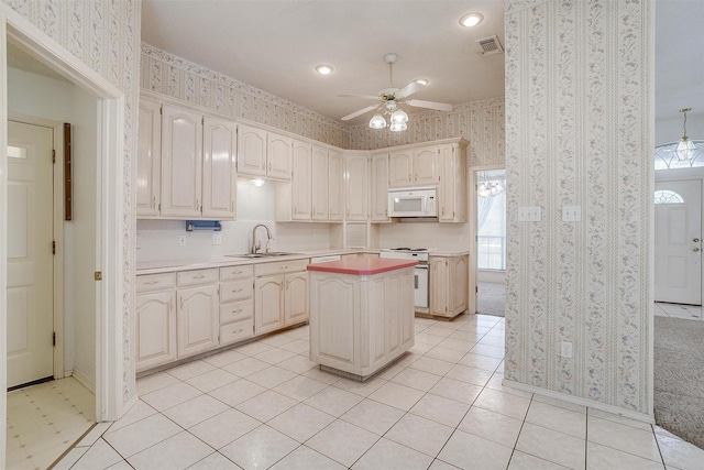 kitchen with ceiling fan, white appliances, a center island, and sink