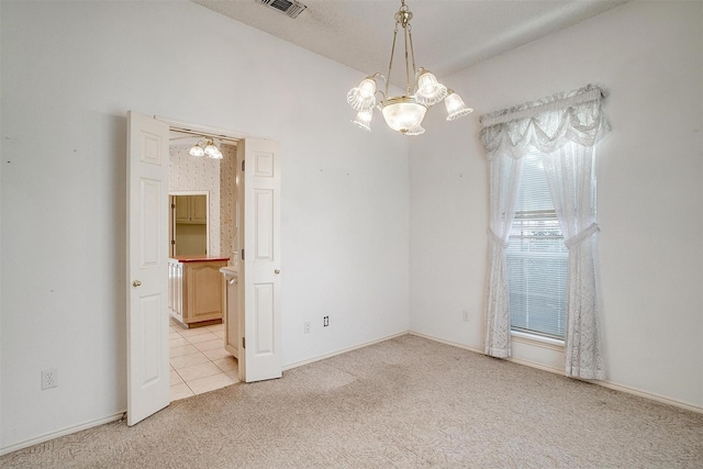 spare room with an inviting chandelier and light carpet