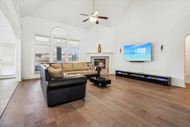 living room featuring a premium fireplace, wood-type flooring, high vaulted ceiling, and ceiling fan