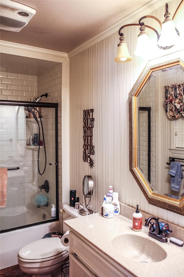 full bathroom with toilet, ornamental molding, vanity, and bath / shower combo with glass door