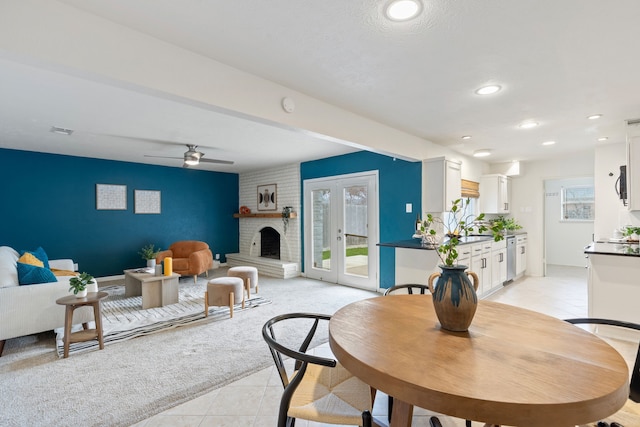 dining room with light carpet, a brick fireplace, french doors, and ceiling fan