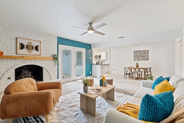 living area with carpet, a fireplace, visible vents, a ceiling fan, and a textured ceiling