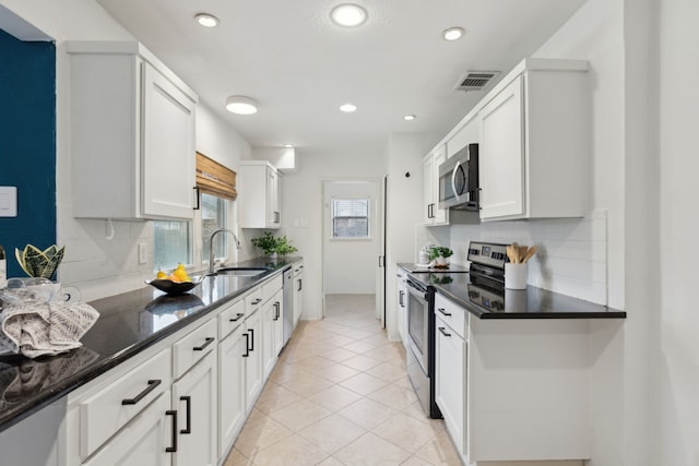 kitchen with stainless steel appliances, a sink, visible vents, white cabinetry, and tasteful backsplash