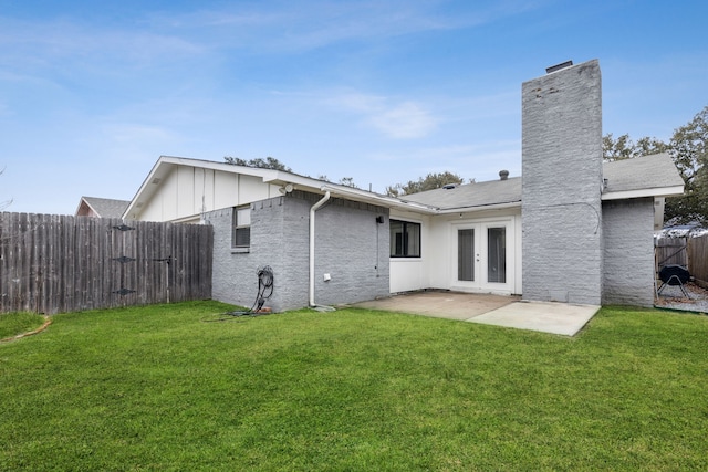 back of house featuring french doors, a patio, and a lawn