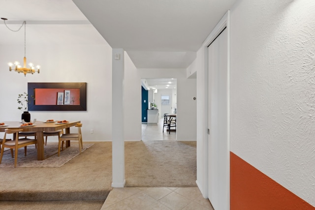 hallway featuring light carpet and an inviting chandelier