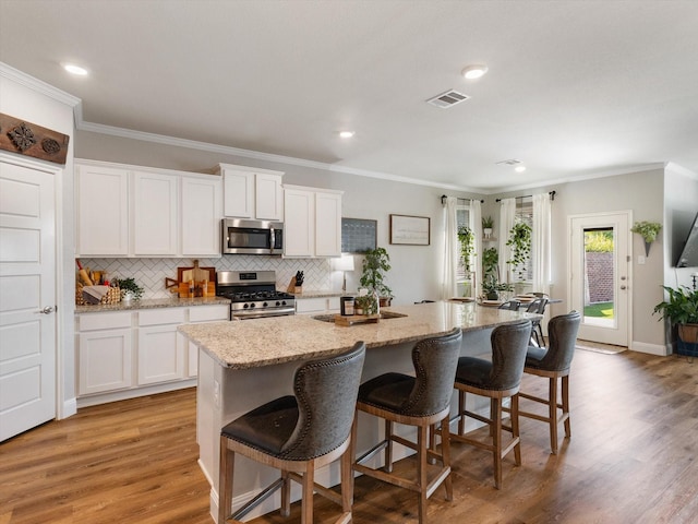 2705 Colorado Dr, Little Elm, TX 75068 - kitchen with stainless steel appliances, an island with sink, crown molding, white cabinets, and tasteful backsplash