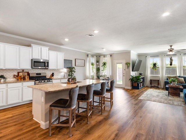 2705 Colorado Dr, Little Elm, TX 75068 - kitchen with appliances with stainless steel finishes, ornamental molding, open floor plan, a kitchen island, and white cabinetry