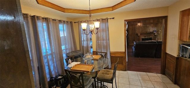 tiled dining area featuring an inviting chandelier, a tray ceiling, a fireplace, and a textured ceiling