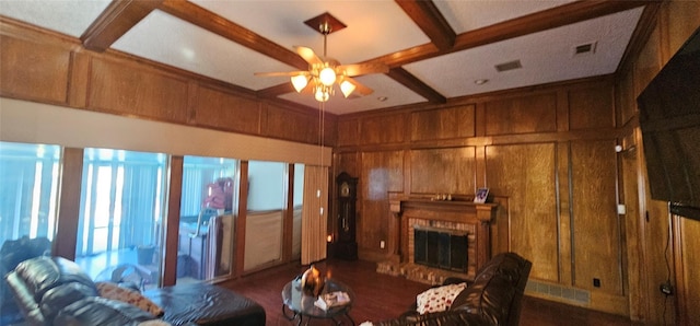 living room featuring ceiling fan, beam ceiling, coffered ceiling, a brick fireplace, and wood walls