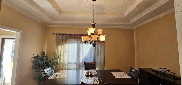 dining space with an inviting chandelier, a tray ceiling, a textured ceiling, and crown molding