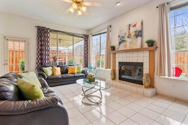 living room with a tiled fireplace, a healthy amount of sunlight, light tile patterned floors, and a textured ceiling