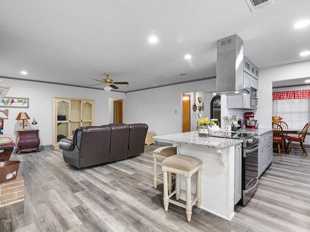 kitchen with electric stove, ceiling fan, gray cabinetry, island range hood, and light wood-type flooring