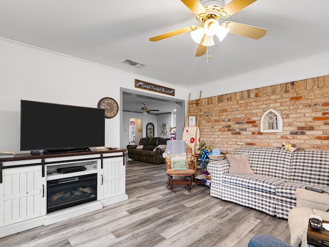 living room featuring ceiling fan, brick wall, and light wood-type flooring