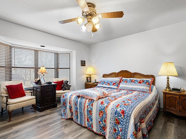 bedroom featuring ceiling fan, hardwood / wood-style floors, and a textured ceiling