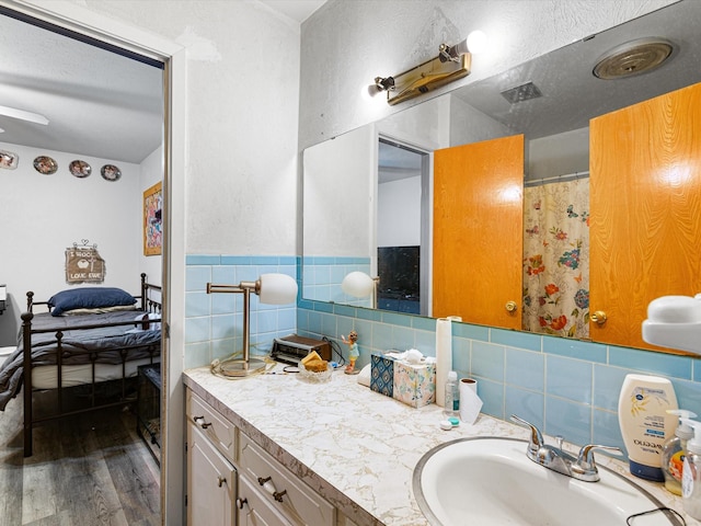 bathroom with vanity, a textured ceiling, wood-type flooring, and tile walls