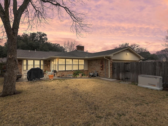 back house at dusk with a jacuzzi and a lawn