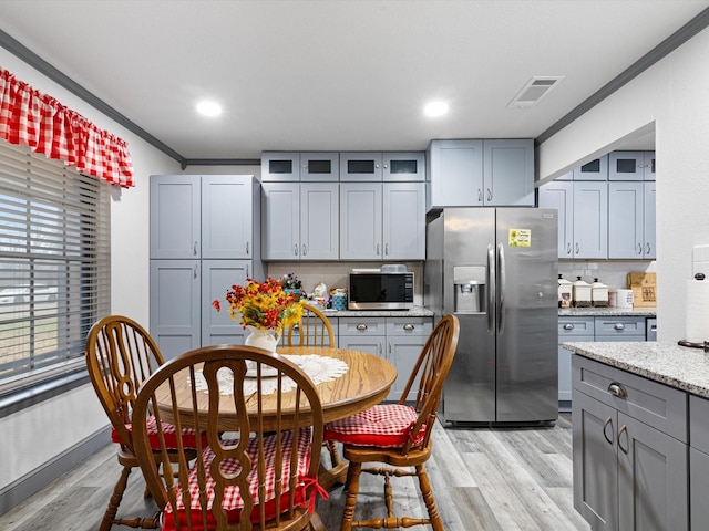 kitchen featuring light hardwood / wood-style flooring, stainless steel appliances, light stone counters, ornamental molding, and decorative backsplash