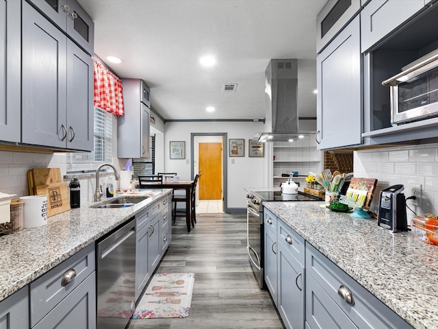 kitchen with extractor fan, sink, backsplash, light hardwood / wood-style floors, and stainless steel appliances