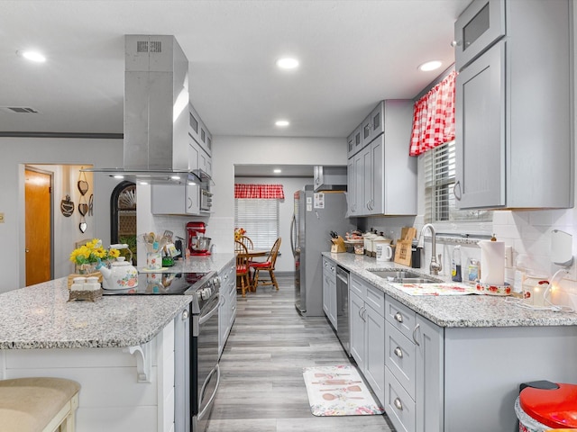 kitchen featuring sink, a breakfast bar area, island exhaust hood, stainless steel appliances, and backsplash