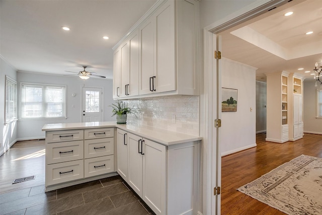 kitchen featuring tasteful backsplash, white cabinetry, dark hardwood / wood-style flooring, ceiling fan, and kitchen peninsula