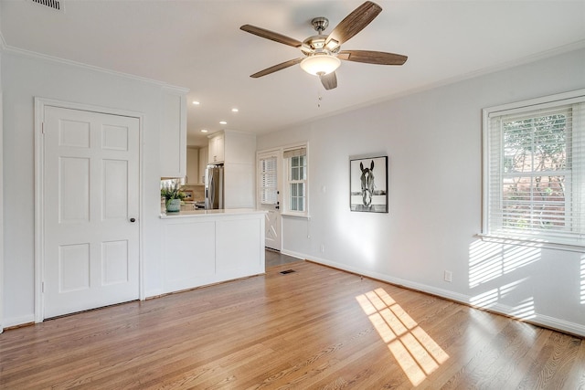 unfurnished living room featuring ceiling fan, crown molding, and light wood-type flooring