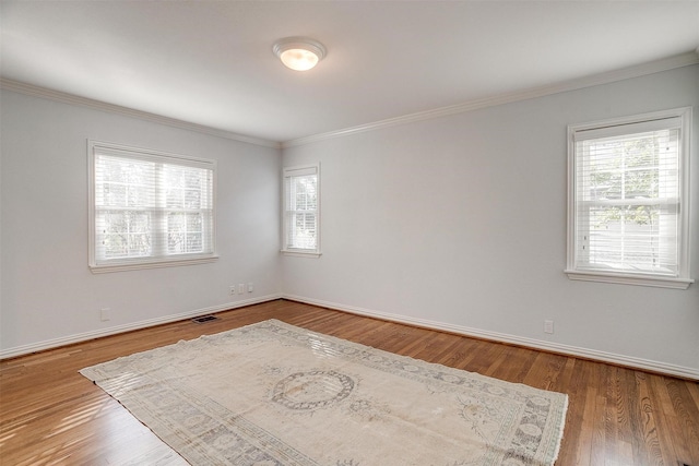 unfurnished room with crown molding, plenty of natural light, and wood-type flooring