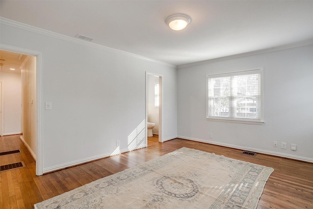 spare room featuring wood-type flooring and crown molding