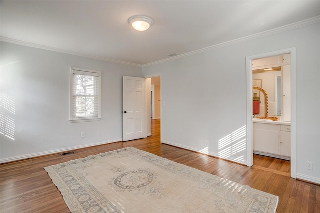 interior space with ensuite bath, ornamental molding, and hardwood / wood-style floors