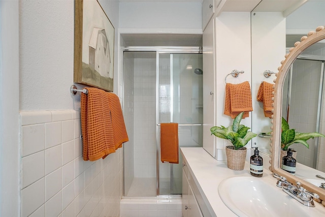 bathroom with vanity, a shower with shower door, and tile walls