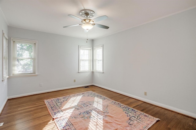 empty room featuring crown molding, ceiling fan, a healthy amount of sunlight, and hardwood / wood-style floors