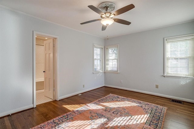 unfurnished bedroom with multiple windows, hardwood / wood-style floors, ensuite bath, and ornamental molding