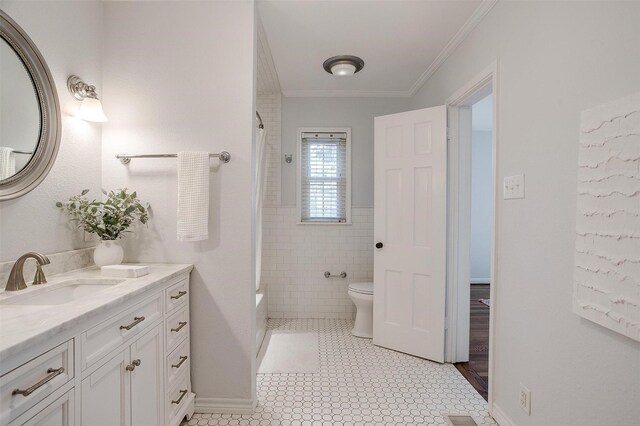 bathroom featuring crown molding, vanity, toilet, and tile walls