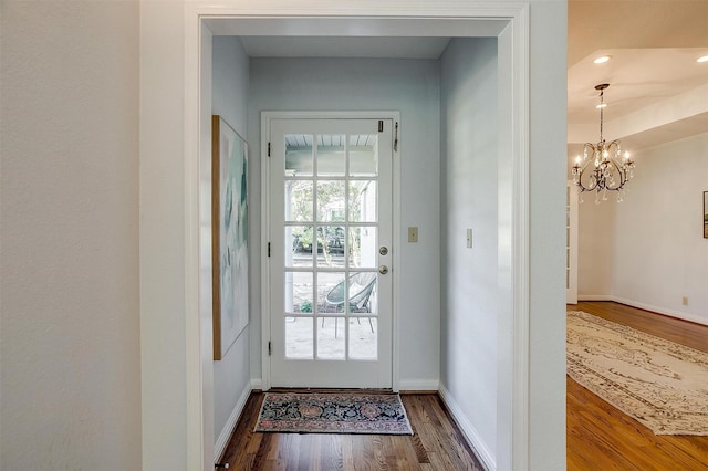 doorway to outside with dark hardwood / wood-style floors and a chandelier