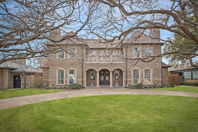 view of front facade with a balcony and a front lawn