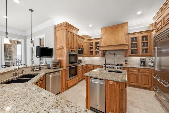 kitchen with pendant lighting, sink, custom exhaust hood, stainless steel appliances, and light stone countertops