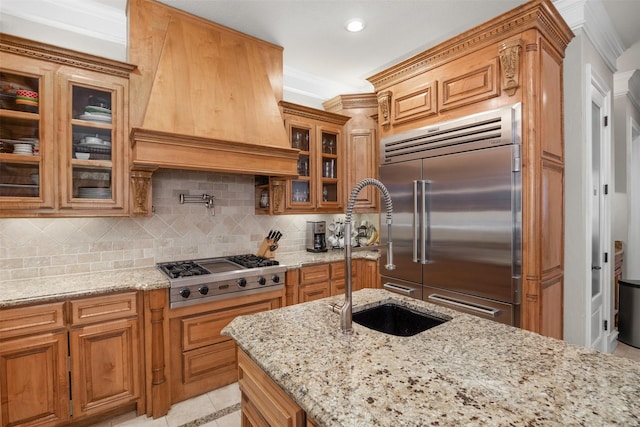 kitchen with sink, custom exhaust hood, stainless steel appliances, and light stone countertops