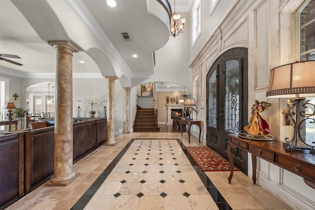 foyer with ornate columns, crown molding, and ceiling fan