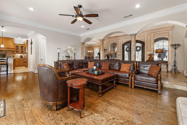 living room featuring crown molding, ceiling fan, wood-type flooring, and decorative columns