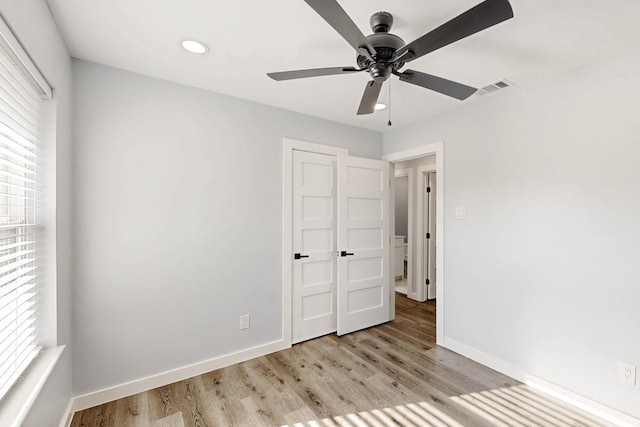 unfurnished bedroom featuring ceiling fan, multiple windows, and light wood-type flooring