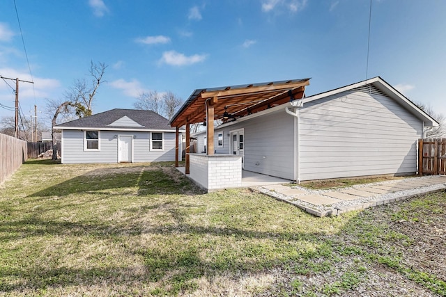 rear view of property featuring an outdoor structure, a lawn, and a patio area