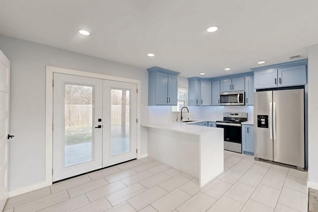 kitchen featuring blue cabinets, sink, kitchen peninsula, stainless steel appliances, and french doors