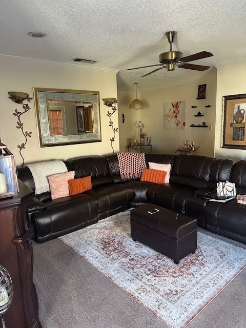 living room with ceiling fan, ornamental molding, a textured ceiling, and carpet