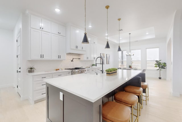 kitchen with white cabinetry, decorative light fixtures, a kitchen breakfast bar, a tray ceiling, and a large island