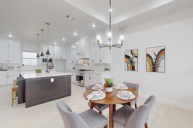 dining space with a notable chandelier, sink, and light wood-type flooring