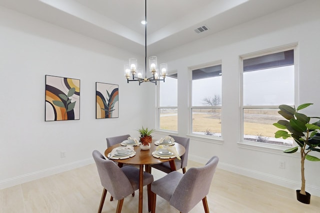 dining room with a raised ceiling and light hardwood / wood-style floors