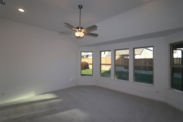 carpeted spare room with lofted ceiling, plenty of natural light, and ceiling fan