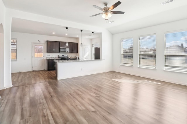 unfurnished living room featuring hardwood / wood-style floors, vaulted ceiling, sink, and ceiling fan