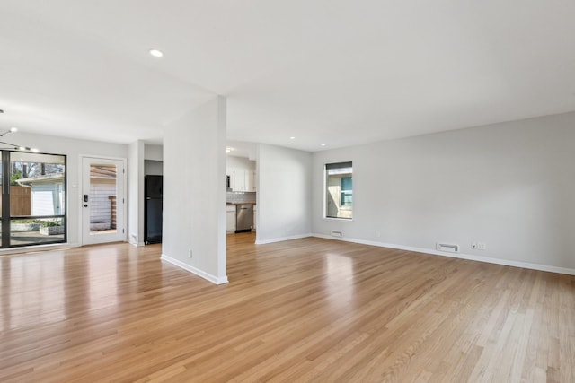 unfurnished living room featuring a chandelier and light hardwood / wood-style floors