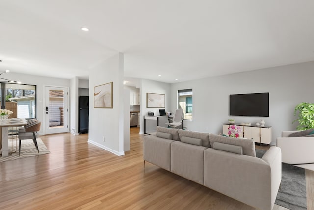 living room with a wealth of natural light, a notable chandelier, and light hardwood / wood-style flooring